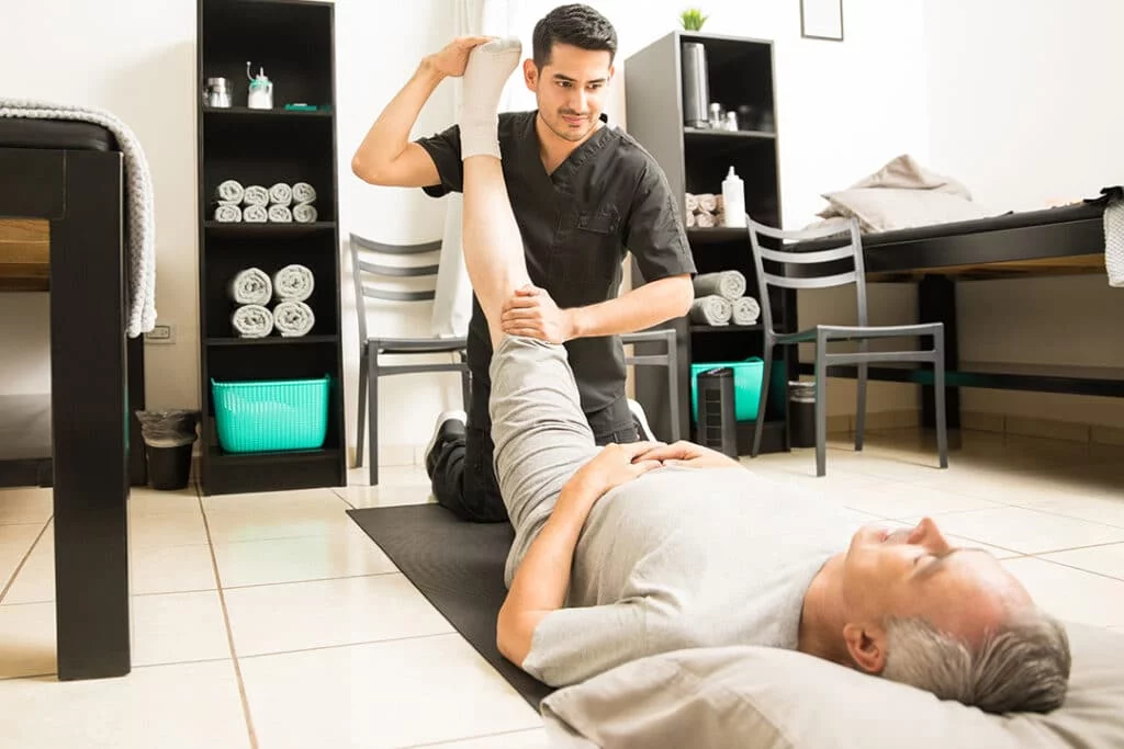 physiotherapy-doctor-assisting-elderly-patient-with-leg-exercise-clinic